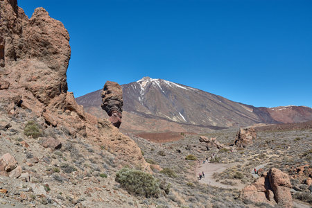 Teide, Tenerife, January 13, 2026, A group of visitors walks along the trails of ocher sand and basalt rocks that extend at the foot of the imposing Mount Teide. The composition uses the contrast between the earthy tones of the volcanic desert and the vibのeditorial素材