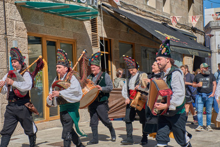 Vigo, Spain, March 28, 2026,A group of musicians dressed in traditional Galician costumes performs popular melodies with bagpipes and drums amidst the festive bustle of Vigo's Reconquista celebrations. The dynamic composition and vibrant colors of the attのeditorial素材