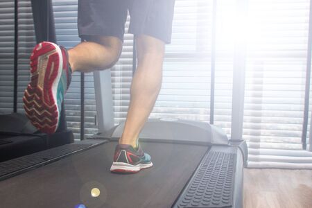 legs of a running man on a treadmill in a sunny morningの写真素材