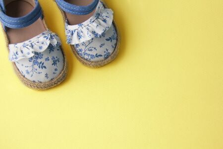 Blue baby shoes on yellow background, enougn space for text, view from topの写真素材