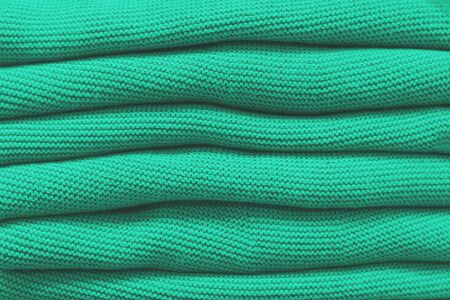 Pile of mint warm knitted sweaters in a raw. Autumn and winter clothes. Good backgraund.の写真素材