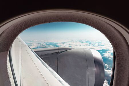 Cloudy view through the aircraft window from the seat at a plane, high at the sky, somewhere at stratosphere.の写真素材