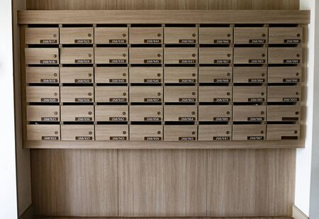 Closeup of numbered mailboxes and lockers in raw in the condo. Natural wooden letterbox panel pattern .の写真素材