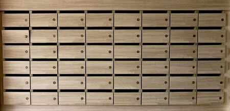 Closeup of unnumbered mailboxes and lockers in raw in the condo. Natural wooden letterbox panel pattern .の写真素材