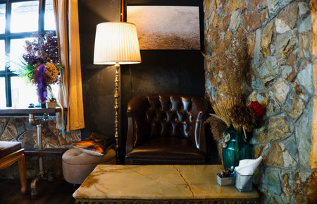 A good place for reading. Interior of a reading room with stone wall, leather cosy comfortable armchair and marble little table. Window at the left.の写真素材