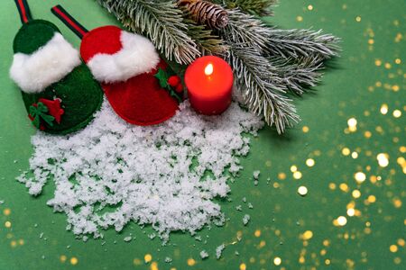 New year and christmas concept. There are slippers, candle, pine branches and snow on green background. View from the top.の写真素材