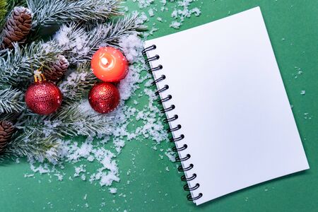 Notebook for goals and future plans before christmas and new year is on green background. There are pine branches, balls and candle near blanl notebookの写真素材