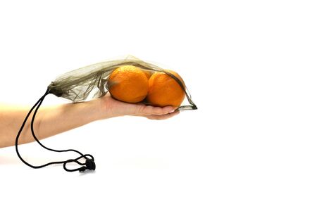 zero wast, no plastic recycled textile handmade bag with drawstring is used for carrying grocery, fruit, vegetables and greens. Mesh bag is on woman hand on white background. eco concept.の写真素材