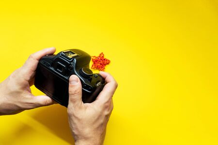 Man takes photo of a little star. There are onky hands, ptoho camera and red star on yellow backgroundの写真素材