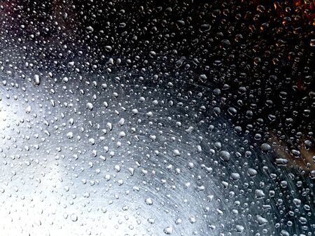 Water drops on scratches transparent glass and little sun shines through the window.の写真素材