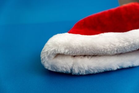 Red and white christmas santa hat lay on blue background on the rigth. Enough space for text.の写真素材