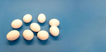 Nine white chicken eggs on blue background, enough space for textm minimal and easter concept. Good for cook recipesの写真素材