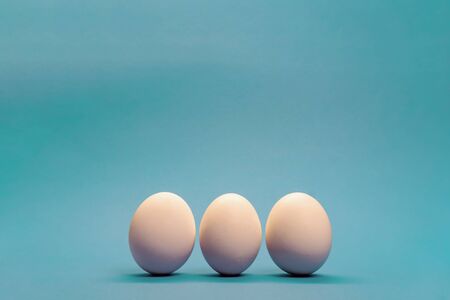 Three white eggs on light blue background, minimal Easter concept, enough space for text.の写真素材