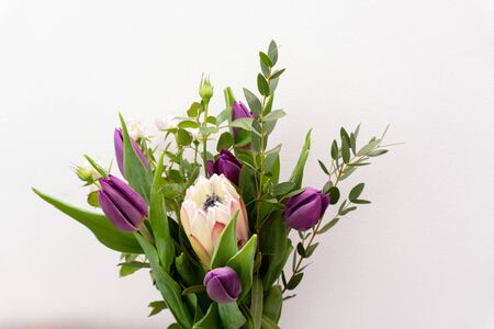 Bouquet of beautiful flowers of tulips, protea, eucalyptus at white background, top view, copy space.の写真素材