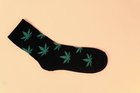 Black socks with cannabis leaves on yellow background, trendy wear, cannabis concept, space for text.の写真素材