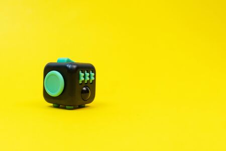 Black and green fidget cube on yellow background, minimal concept, copyspace. の写真素材