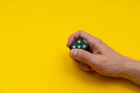 Antistress fidget in mans right hand on yellow background, close up, copy spaceの写真素材