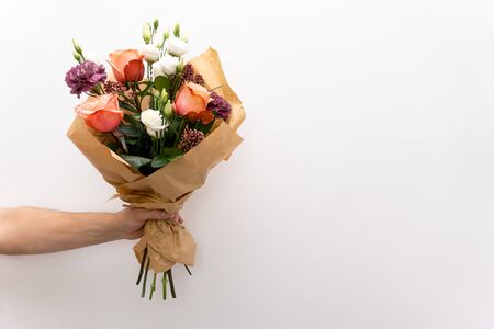 Beautiful bouquet in hands hand on white background. Roses and chrysanthemums.Copy space.の写真素材