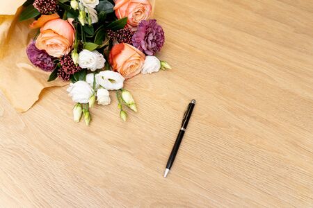Beautiful bouquet on wooden background and a black pen, view from the top. Copy space, place for note book.の写真素材