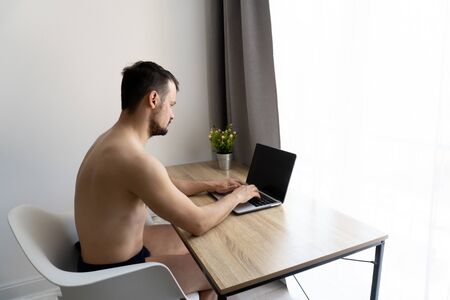 Man in pants should work from home during quarantine time because of coronavirus epidemia. He is freelancer. White backgroundの写真素材