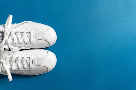 White unisex shoes sneakers on the left on trendy classic blue color background, copy space, top view.の写真素材