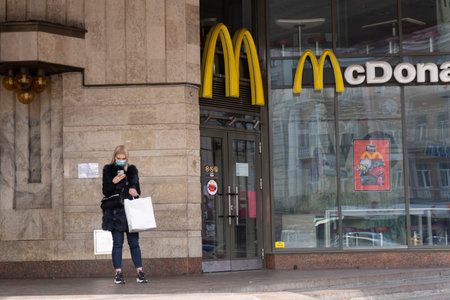 Kiev, Ukraine, March 27, 2020, young fashion girl stands near mcdonald restaurant and looks at cell...