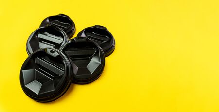 Coffee balck cover lids lay on each other on yellow background. Closeup, copy space.の写真素材