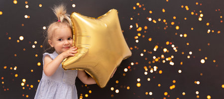 Cute blond caucasian baby with star balloon in hands at black bokeh background, christmas concept,...