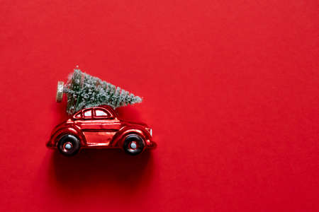 Closeup of red Christmas car with green fur tree on the top of the car on red background, copyspace, Christmas mood.の写真素材