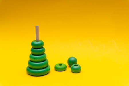 Pyramid build from green children wooden toy rings at yellow background, toy for baby and toddlers. Child development concept.の写真素材