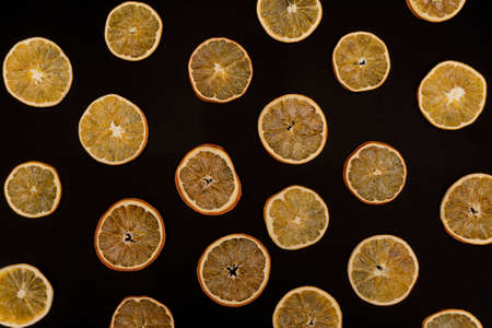 Repetitive pattern of dried oranges and tangerines at black background, view from the top, creative concept, eco life.の写真素材