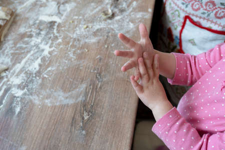 Hands of little caucasian kid trying to cook or play with flour at the table at kitchen, cooking family concept, copy space.の写真素材