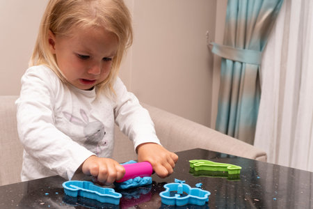 Crying kid plays with colorful dough, making animals, cute upset and sad caucasian child.