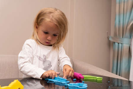 Crying kid plays with colorful playdough, making animals, cute upset and sad caucasian child.の写真素材