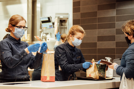Kiev, Ukraine, October 16, 2021, staff of McDonalds restaurant gives customers their takeaway orders. Workers are in protective medical masks and blue latex gloves.のeditorial素材