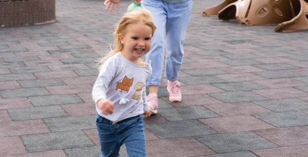 Cute caucasian child runs away from mom, family activity for fun, family games at playground.