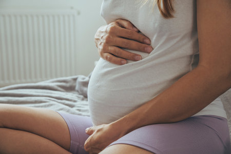 Young pregnant woman sitting on a sofa, view from a side.の写真素材