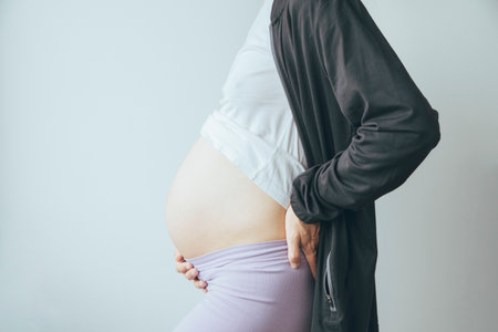 Young woman with pregnant belly, view from a side.の写真素材