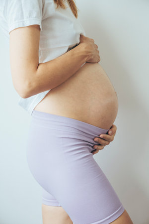 Young woman with pregnant belly, close up, view from a side.の写真素材