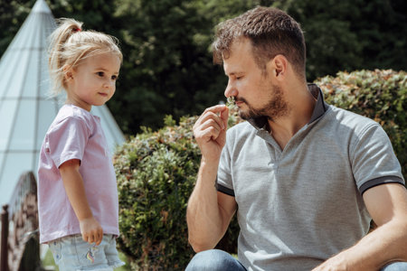 Little caucasian four years girl giving a little flower to her father at Fathers day. Father smells the flower. Summertime.の写真素材