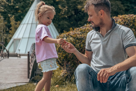 Little caucasian four years girl giving a little flower to her father at Fathers day. Family love. Summer time.の写真素材