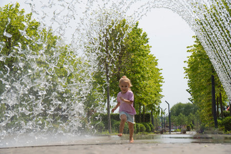 Little caucasian child running near fountain, barefoot. Happy smiling face. Summer time. Shot in motion.の写真素材
