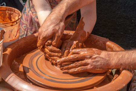 potter teaches to sculpt in clay pot on a turning pottery wheelの写真素材