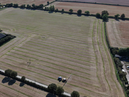 an aerial view of a tractor spraying a large field