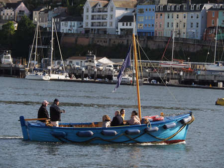 a small blue ferry boat taking passengers on the River Dart in Dartmouth, Devon
