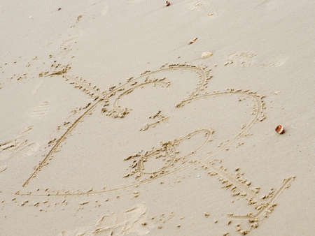 An arrow with a heart through it drawn in the sandの写真素材