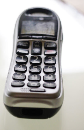 A modern landline handset seen resting on a white table