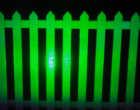 Semiabstract picture of a green coloured picket fence isolated against a black backgroundの写真素材