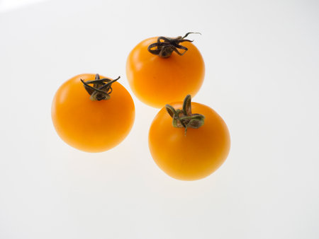 Studio picture of golden yellow tomatoes against a white backgroundの写真素材