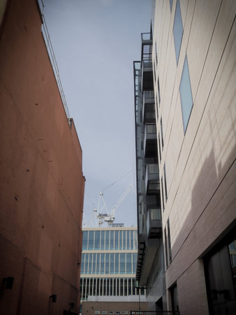 a tower crane seen framed by mixed modern glass and brick office buildings